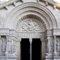 Ce portail sculpté est ajouté à l’église entre 1180 et 1190. Avec la façade de l’abbaye de Saint-Gilles qui lui est très légèrement antérieure, il constitue un des deux plus grands ensembles sculptés de l’art roman en Provence. Le tympan de Saint-Trophime