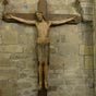 Le crucifix roman: On trouve dans certaines églises de l'Auvergne méridionale de grands crucifix en bois de style roman (fin XIIe). Celui d'Auzon, un peu plus grand que nature, mesure 1,90m .Le Christ est cloué à la croix par quatre clous. il est vêtu d'une sorte de jupe tombant jusqu'au genoux. Les bras sont étendus, presque à l'horizontale, les mains largement ouvertes (les doigts ont une réfection moderne). La tête, très noble, est légèrement inclinée sur la doite: les yeux ne sont pas fermés - ils ne le sont jamais à l'époque romane. Les cheveux tombent sur les épaules . Chose curieuse, dans les crucifix de cette série, les jambes sont rapportées et articulées sous la jupe.